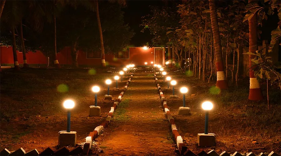 Lit pathway to cottages at night at Dandeli River Edge Resort