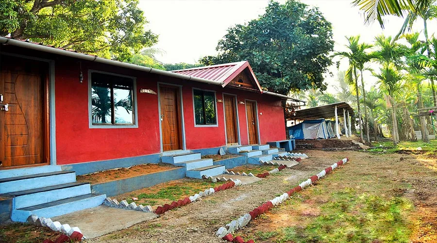 Red cottage rooms and tent shelter at Dandeli River Edge Resort, Kerwad