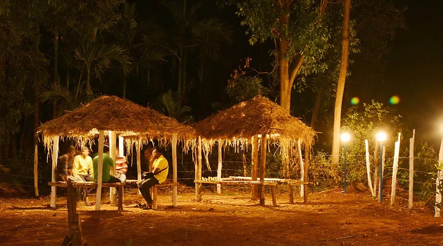Thatched hangout pavilions at night at Dandeli River Edge Resort