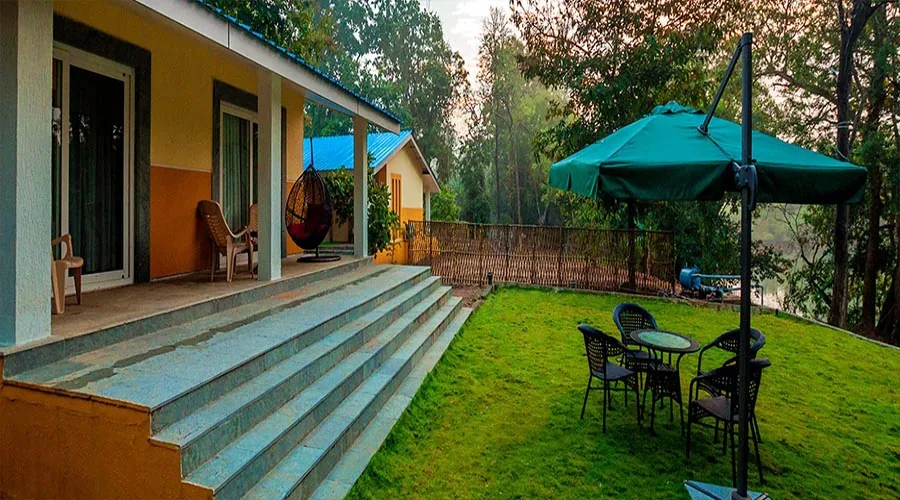 Cottage lawn and porch facing the forest at Whistling Woods Dandeli