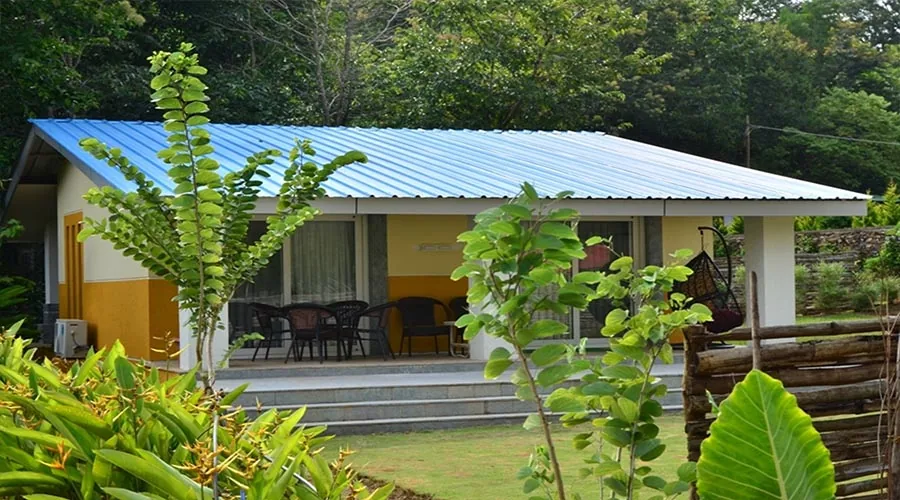 Cottage porch with hanging egg chair at Whistling Woods Dandeli