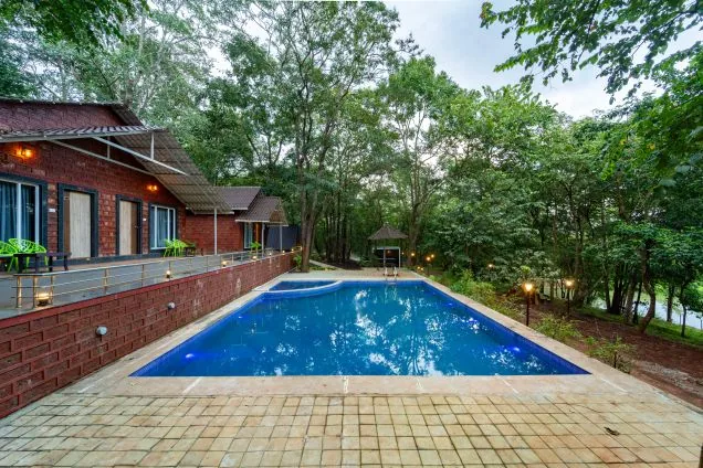 Pool deck facing forest cottages at Jungle View Cottage Dandeli